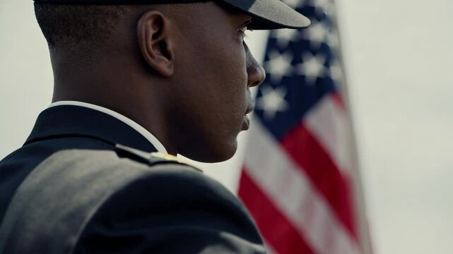 Young soldier stands at attention, his gaze fixed on the american flag waving majestically in the background, embodying patriotism and military service - Powered by Adobe