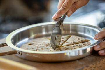 A person is cutting a tortilla with a pizza cutter