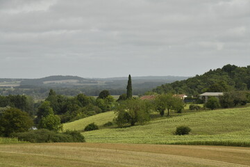 Paysage rural de collines boisées et de champs en pente sous un ciel gris près du bourg de Champagne au Périgord Vert  © Photocolorsteph