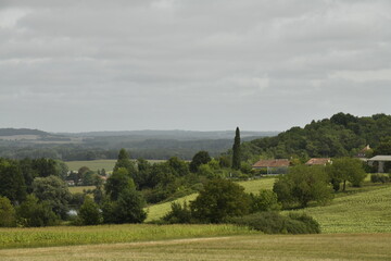 Paysage rural de collines boisées et de champs en pente sous un ciel gris près du bourg de Champagne au Périgord Vert  © Photocolorsteph