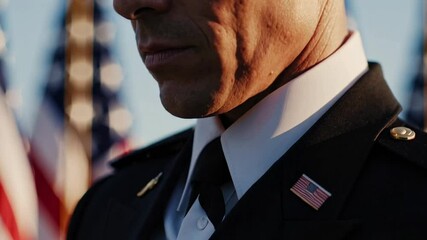 Close up of a thoughtful military officer's face, standing in uniform with several american flags waving gently in the background, evoking patriotism and remembrance