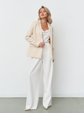 Elegant female model posing in stylish neutral suit within modern studio setting