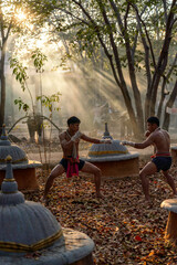 Traditional Muay Thai Fighters Training in Forest Temple. Martial Artists Practicing Kickboxing at Sunset in Rural Thailand.