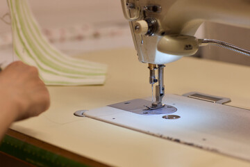 A Focused Seamstress Diligently Working with a Sewing Machine in Her Creative Workspace
