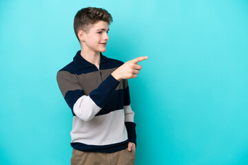 Teenager Russian man isolated on blue background pointing finger to the side and presenting a...