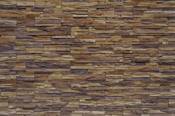 Wall made of brown and beige vintage bricks. The bricks are laid in a pattern.