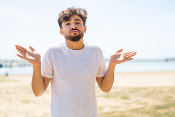 Handsome Arab man at outdoors making doubts gesture