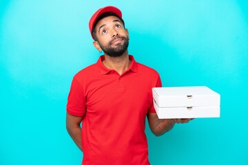 Pizza delivery Brazilian man with work uniform picking up pizza boxes isolated on blue background...