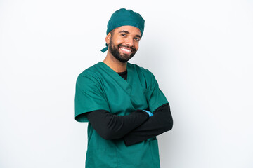 Surgeon Brazilian man in green uniform isolated on white background with arms crossed and looking...