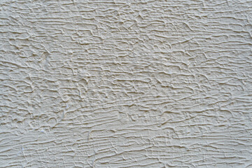 A wall with a white paint that has a texture. The texture is made up of lines and swirls.