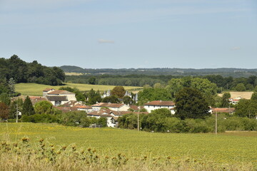 Obraz premium Le village de Champagne en contrebas d'un vaste champ de tournesol au Périgord Vert 