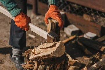 Pensioner man strong lumberjack in gloves chopping trees, log with axe in forest at sawmill in...