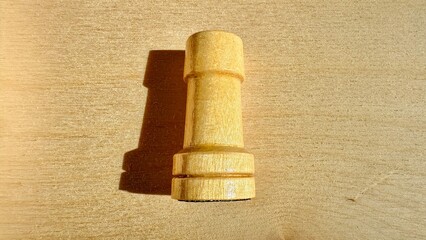  wooden rook chess piece casting shadow on light textured surface for web design, branding, game strategy, print media, and educational graphics