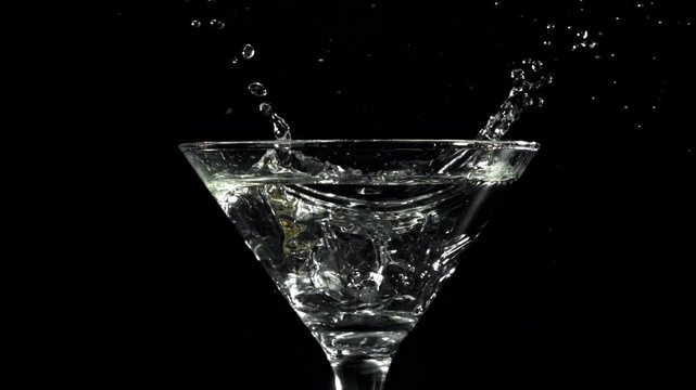 Ice falls into a martini glass. Filmed on a high-speed camera at 1000 fps. High quality FullHD footage