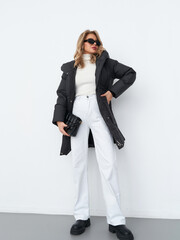 Stylish woman poses confidently in a studio, showcasing contemporary fashion trends