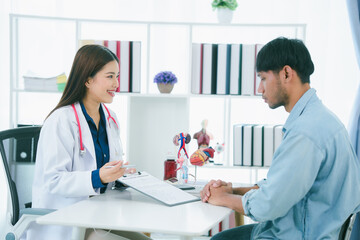 Fototapeta premium Asian female doctor examining male patient who is suffering from stomach pain, digestive problems, heart disease.