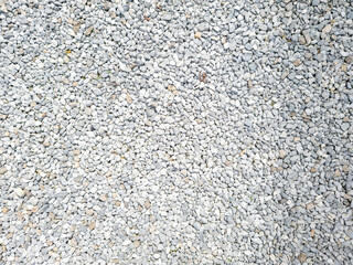 A close-up view of small, light gray gravel stones covering a surface, ideal for landscaping and...