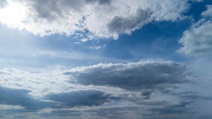 Cloudy sky with varied cloud formations and sunlight breaking through, creating a tranquil atmosphere. Ideal for nature and weather-themed projects.