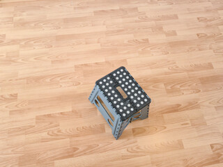 A foldable step stool with a dotted surface sits on a wooden floor, providing a practical solution for reaching high places in home or office settings.