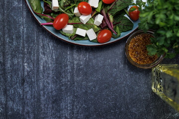 healthy eating concept, aesthetic view from above. food photo of a fresh salad of cherry tomatoes, cubes of white cheese and greens on a textured background. Nearby, a small bowl of grainy mustard 
