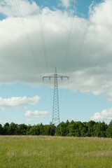 Free-standing high-voltage pylon in Germany with power lines, with green foreground and blue sky