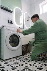 man doing laundry in the bathroom loading washer with clothes