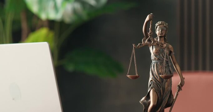 Lawyer's office. Statue of justice with scales and a laptop in a modern office cubicle. Concept of legal law, counseling and concept of justice.