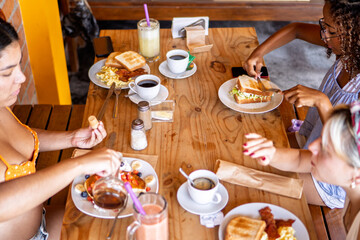 Friends enjoying breakfast at wooden table during trip