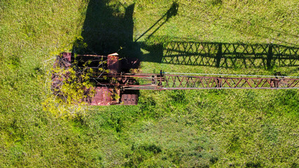 Abandoned crane on a meadow while nature is taking it back, seen from above