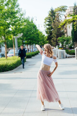 Fototapeta premium Blonde in dress dancing to music on street