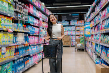 Happy customer doing grocery shopping, walking through supermarket aisle, choosing cleaning products