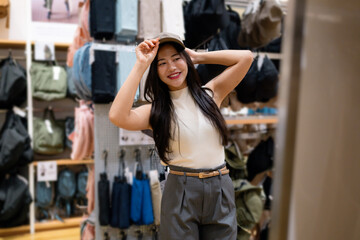Happy customer adjusting her cap in front of a mirror, enjoying her shopping experience in a fashion store