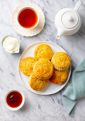 Scones with jam, clotted cream and cup of tea. Marble background. Top view.