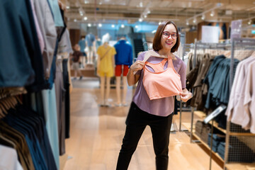 Customer choosing clothes in a store, holding a salmon-colored sports bra