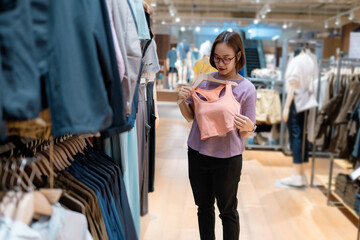 Young woman choosing sport bra in clothing store