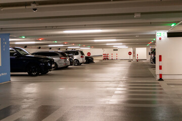  Parking garage interior showcasing parked cars, illuminated signs, and directional indicators for...