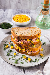 Tuna and corn salad on grain bread on a plate on a table vertical view