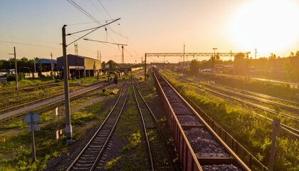 Naklejka premium Sunset Over Train Tracks and Railway Yard with Lush Greenery