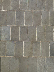 Monohcrome grey rectangular outdoor tiles with random shades and roughness. Suitable for exterior garden flooring. Seamless background texture.