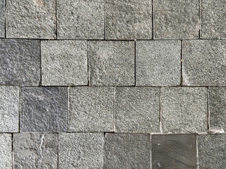 Close up of flat andesite slate stone or grey paving stone. Suitable for wall finishes, cladding, or outdoor floor materials. Good for pavement and sidewalk. Seamless background texture.
