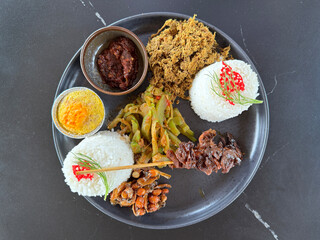 Balinese tradidional food, shredded chicken Betutu with Matah Chili sauce. Chicken Betutu is a famous chicken dish from Bali with skewers and seasoned peanuts and vegetable dressing.