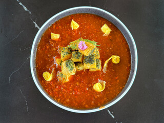 Close up of mapo tofu with deep red sauce. Mapo tofu is a typical Chinese Hakka cuisine originating in southern china. Served on a grey plate, on a black marble table.