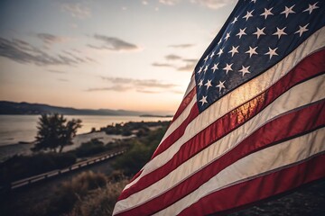 American flag waves proudly against a beautiful sunset over a calm lake landscape