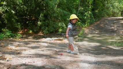 Fototapeta premium A cheerful Asian child girl with a butterfly net enjoys a sunny day in the forest, ready for an adventure Exploring in nature.