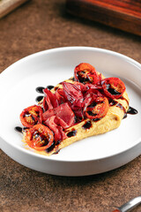 Portion of gourmet hummus with bresaola and sun-dried tomatoes