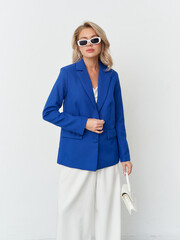 Fashion-forward female model showcases stylish blue blazer in modern studio setting