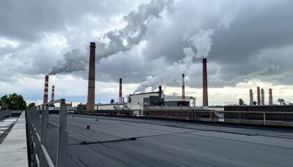 Obraz premium Industrial Landscape with Smoke Stacks and Cloudy Sky View