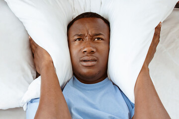 Snoring, insomnia, bad sleep, loud neighbors. Upset tired young african american man freaking out,...