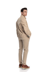 Fototapeta premium sexy young man looking behind while walking with hands in pockets
