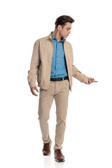 Fototapeta premium sexy fashion guy in beige jacket looking down side and walking